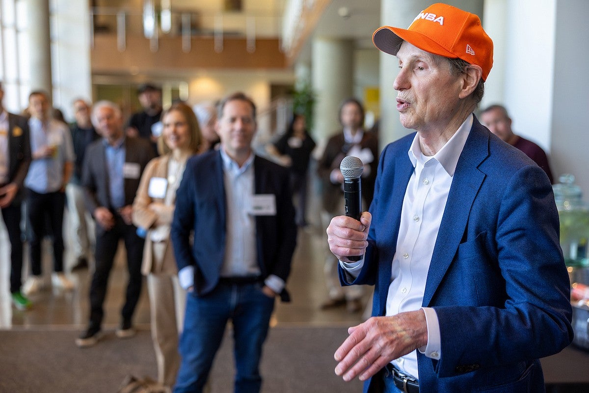 man speaking into a microphone as people watch
