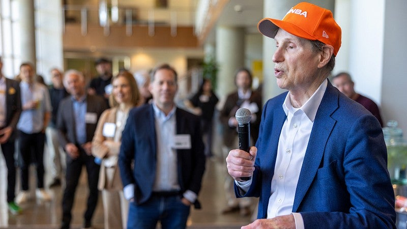man speaking into a microphone as people watch