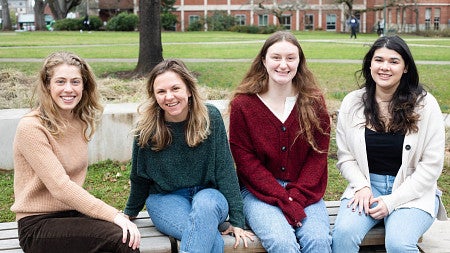 four young women posing on outdoor bench