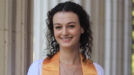 portrait of female student in graduation stole posing in front of white columns