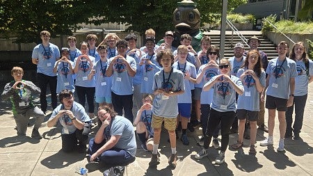 group of students standing in front of Duck statue throwing the O