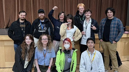 group of students standing in front of a stage posing for camera