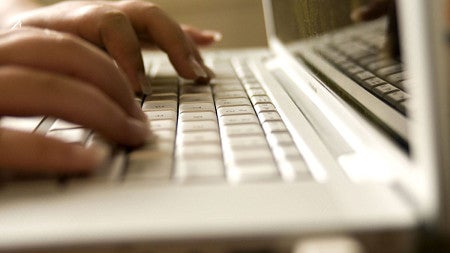 fingers typing on computer laptop keyboard