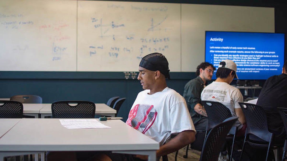 student reading from papers on table in classroom