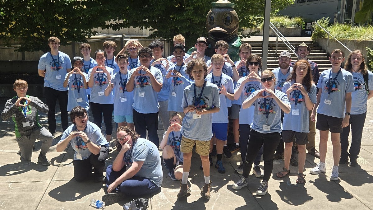 group of students standing in front of Duck statue throwing the O