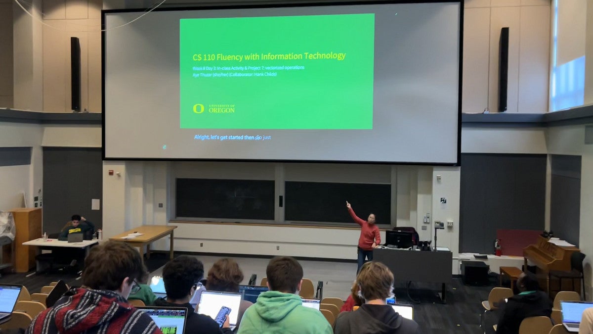 lecture class with green slide on the screen and professor pointing to it