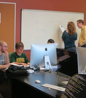 2 students working on computer and 2 students working on whiteboard in background at 2015 Luks Programming Contest