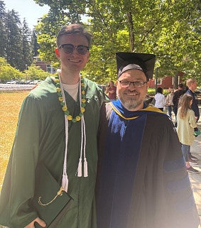 student in graduation regalia posing with professor also in regalia