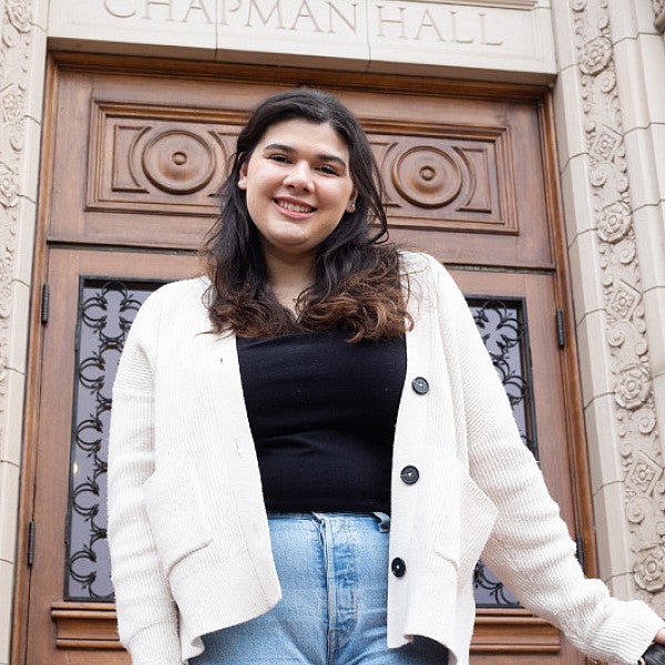 female student posing on steps of chapman hall in front of ornate wooden door