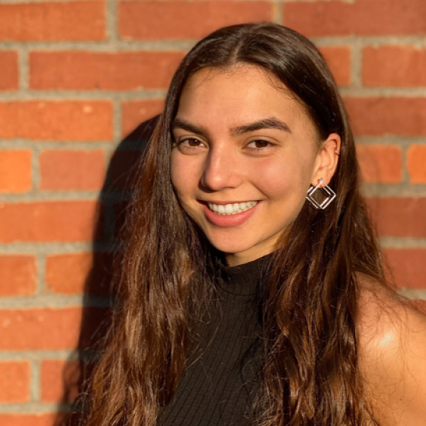 portrait of smiling female student in front of brick wall