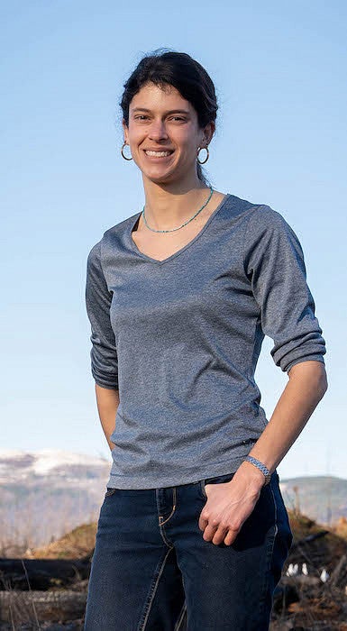 woman smiling in front of snowcovered distant mountains