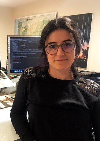 student posing in front of multiple screens displaying code