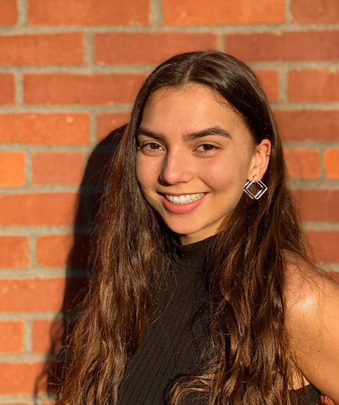portrait of smiling female student in front of brick wall