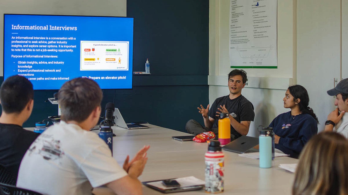 students around classroom table discussing a slideshow about informational interviews