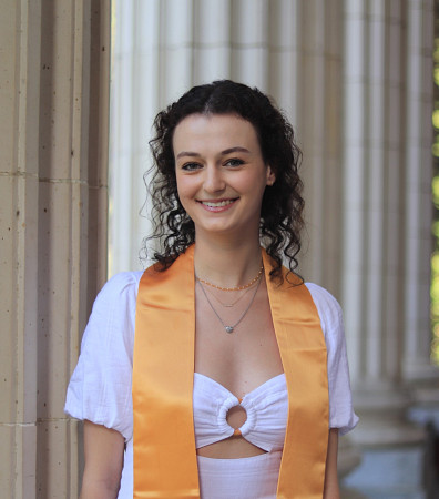 portrait of female student in graduation stole posing in front of white columns